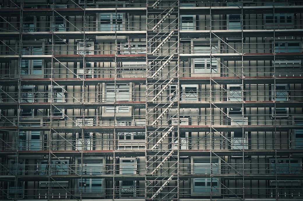 Fassadengerüst über die volle Höhe eines Wohnblocks, mit durchgehenden Treppenläufen zwischen den Ebenen